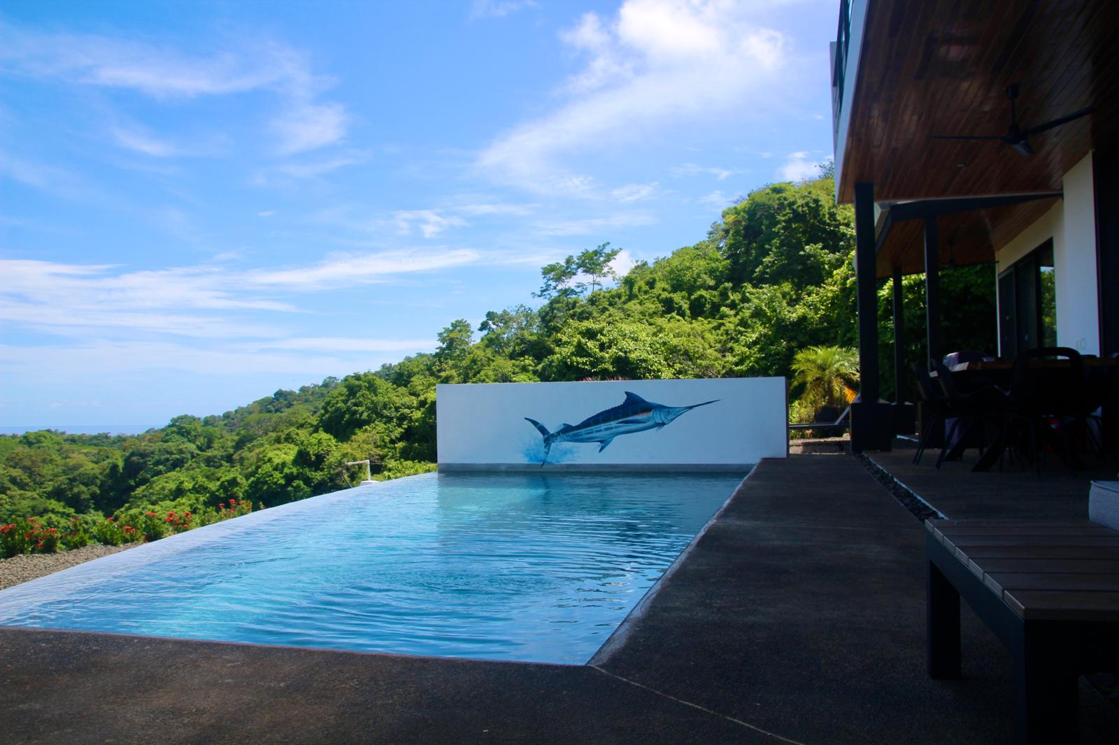 Casa Playa Carrillo — infinity-edge pool and marlin mural looking out over the forest canopy