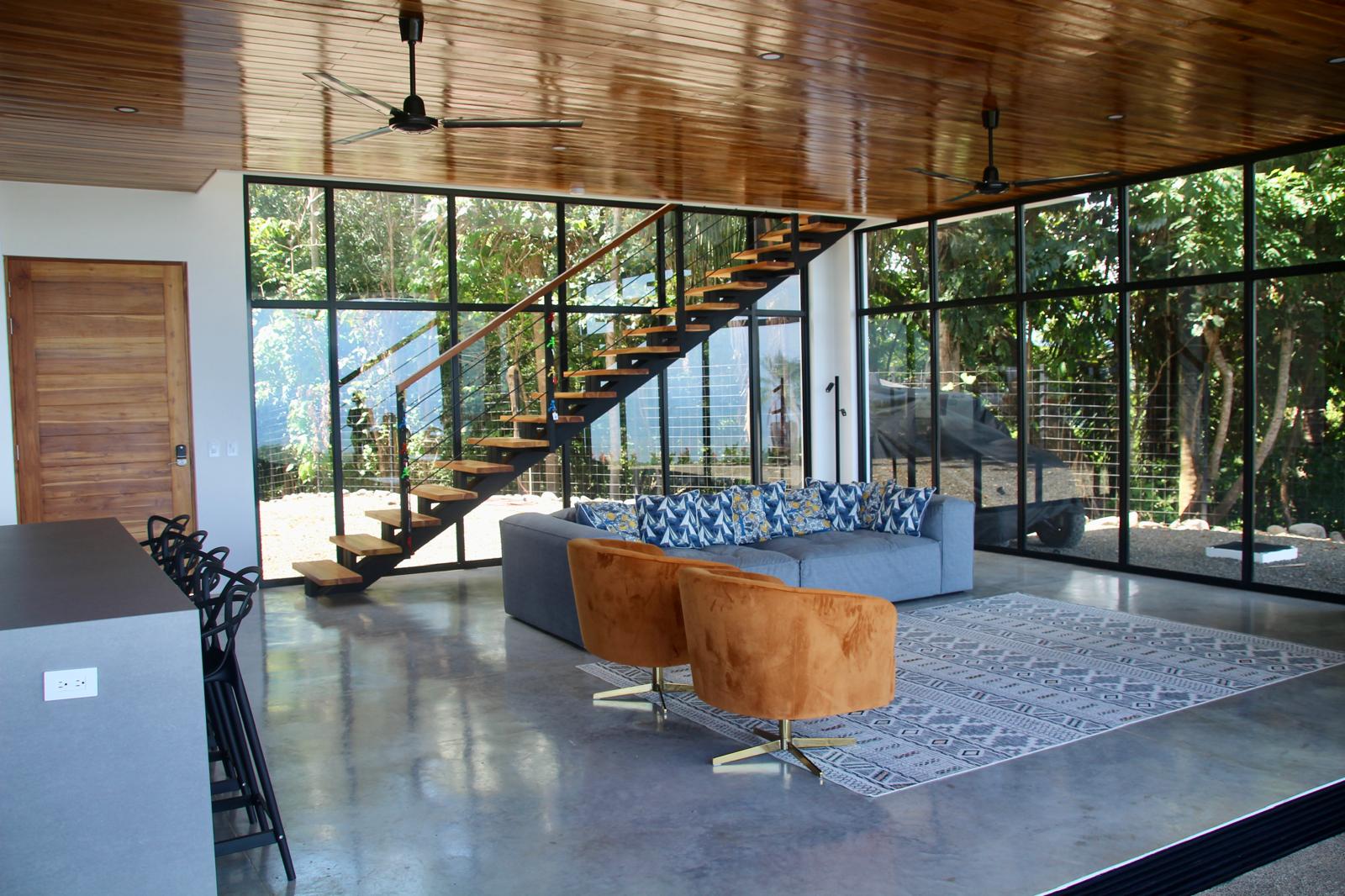 Casa Playa Carrillo — great room with timber ceiling, floating teak stair and black-framed glass walls