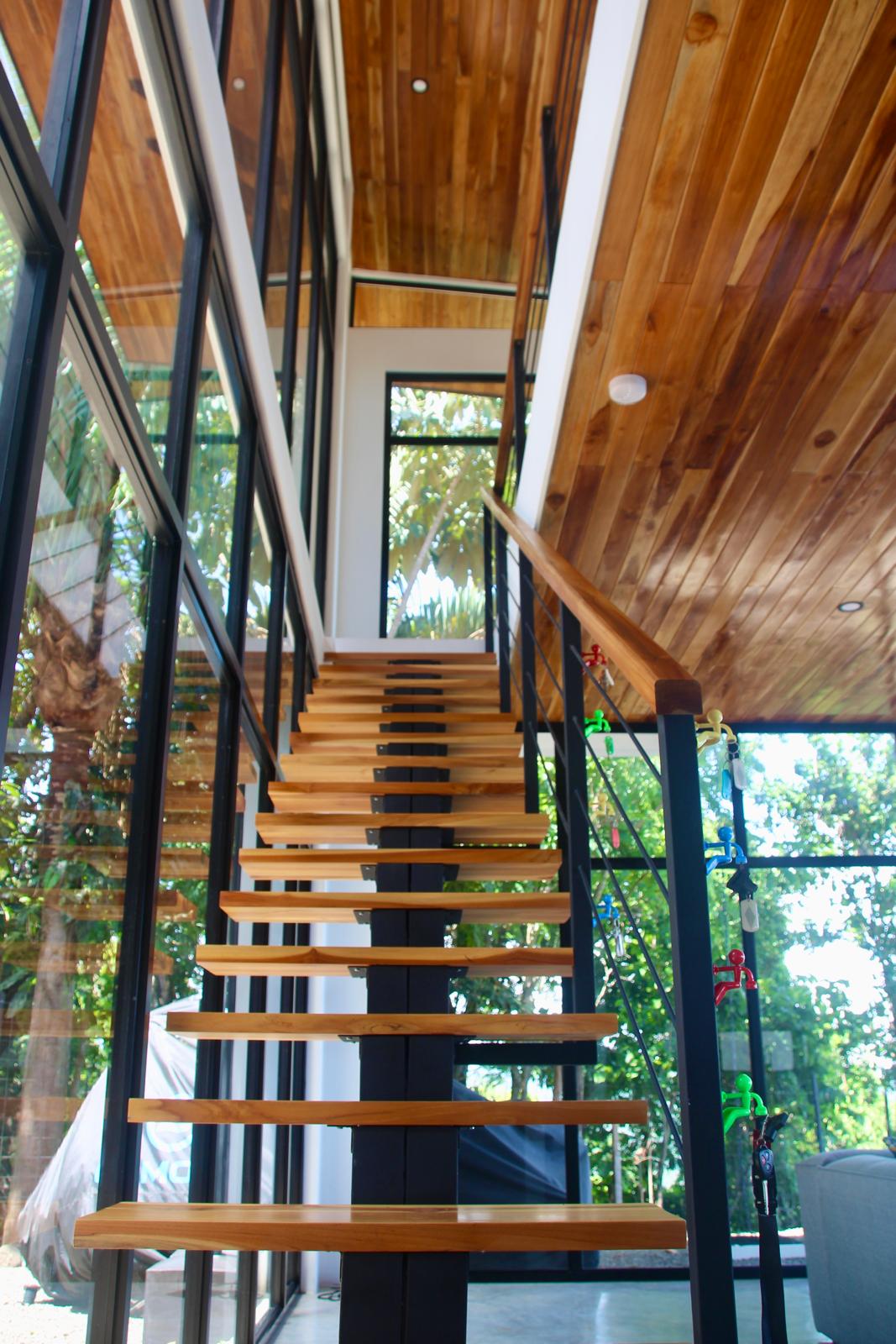 Casa Playa Carrillo — floating teak stair rising through the double-height glazed volume