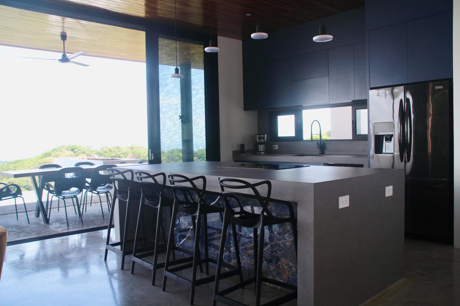 Casa Playa Carrillo — kitchen island and bar seating opening onto the covered dining terrace