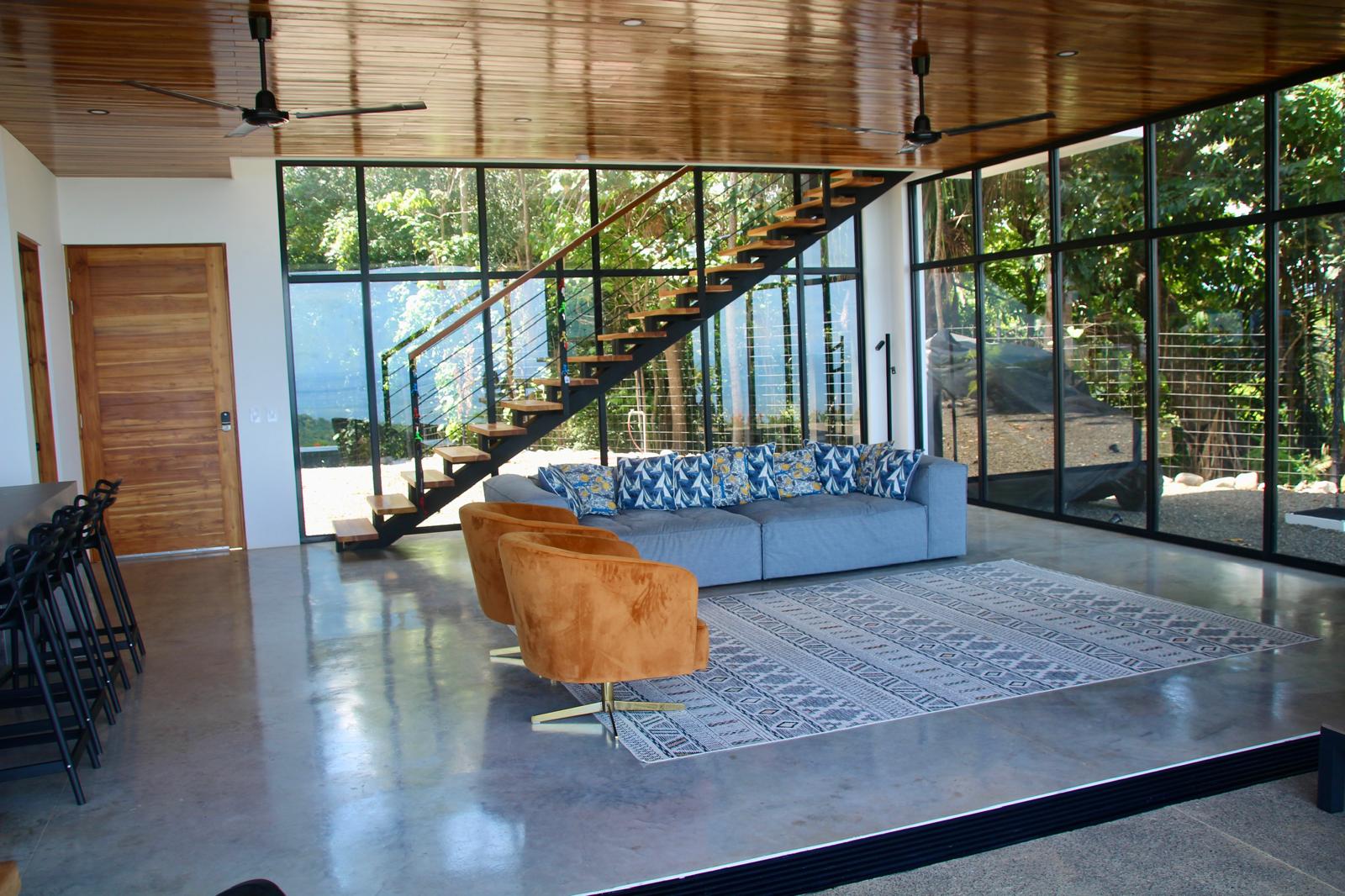 Casa Playa Carrillo — living area seen from the kitchen, with the stair and full-height glazing beyond