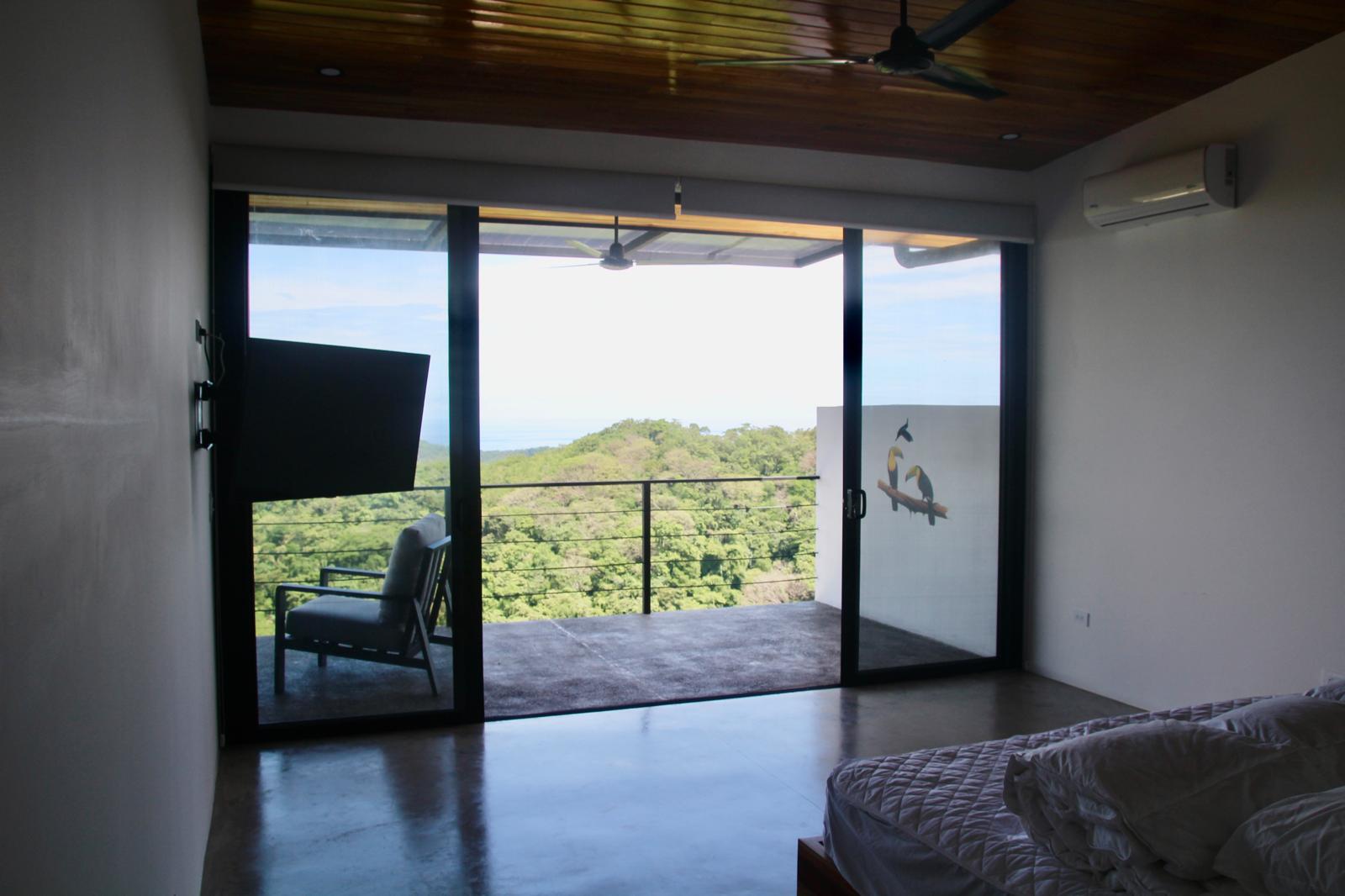 Casa Playa Carrillo — bedroom with sliding doors opening onto the balcony above the forest canopy