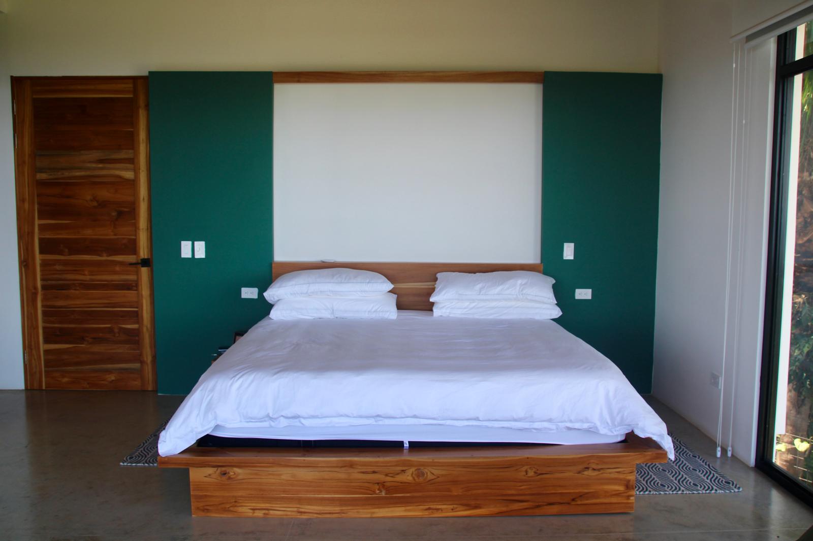 Casa Playa Carrillo — bedroom with green feature wall, teak platform bed and teak door