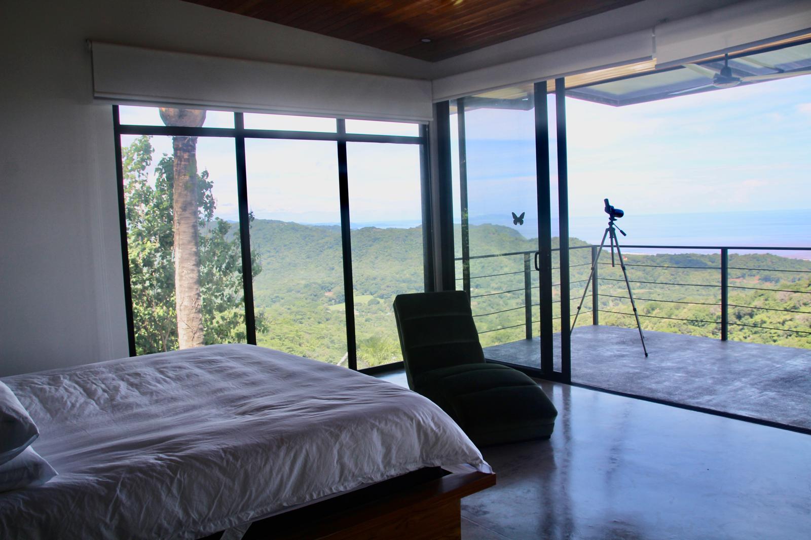 Casa Playa Carrillo — bedroom opening to the terrace with a panoramic view over the treetops to the coast